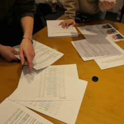 Three BetaNYC staff members spread out papers on a wooden table.