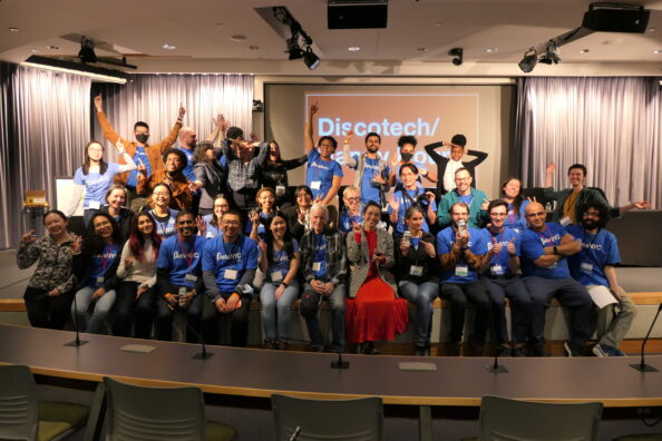 2024 School of Data Volunteers pose together on a stage in an auditorium at CUNY School of Law.